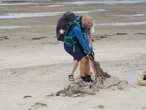 Kraftvoller Einsatz beim Räumen von Netzresten im Sand, die oft tief und breitflächig von den Gezeiten und Stürmen eingegraben werden Foto: © Holger Haake